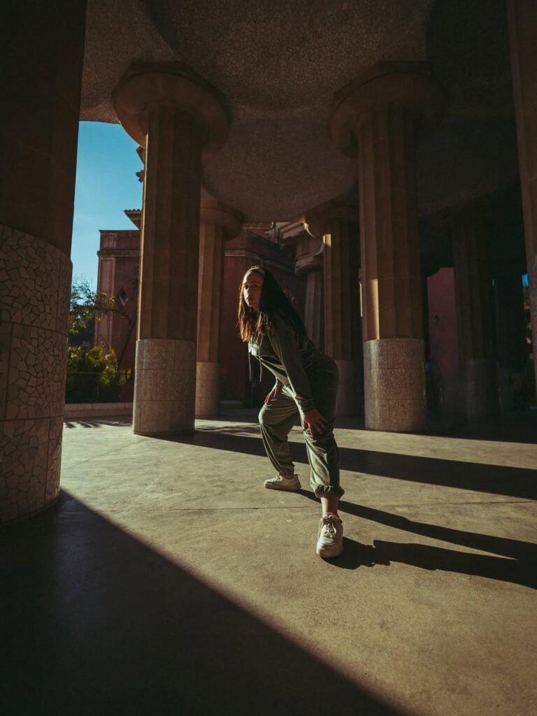 Arantxa Styles en un look deportivo bajo columnas arquitectónicas con luz del sol.