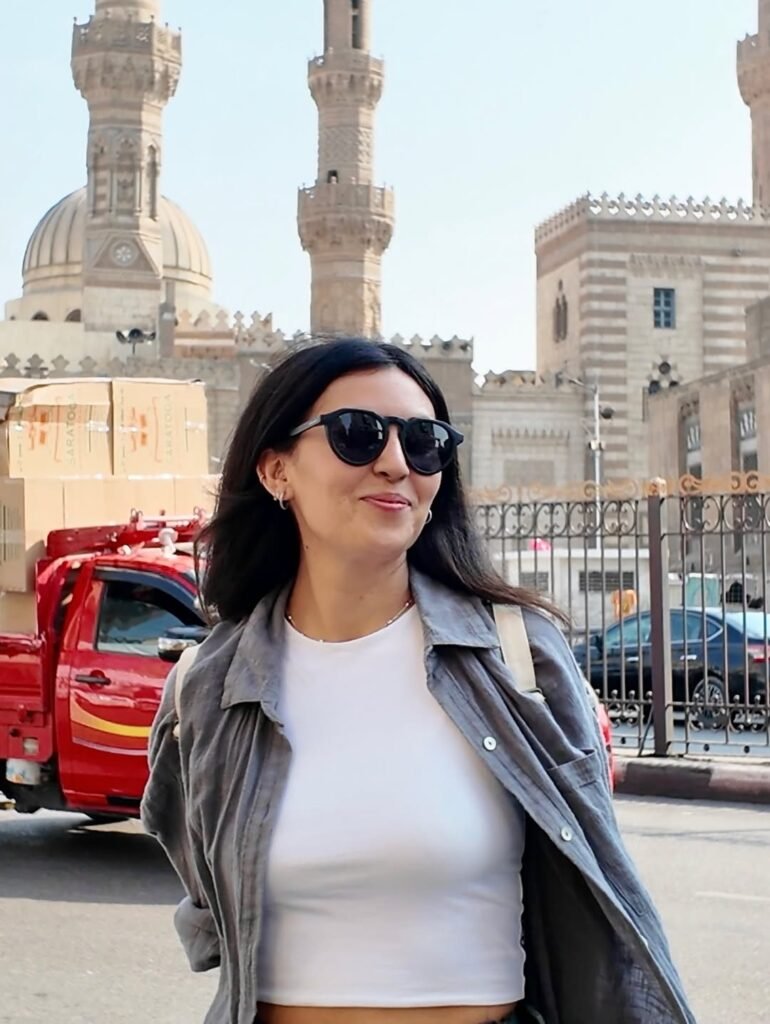 Fátima del Pilar posando con gafas de sol frente a una arquitectura tradicional, disfrutando de su experiencia viajera.