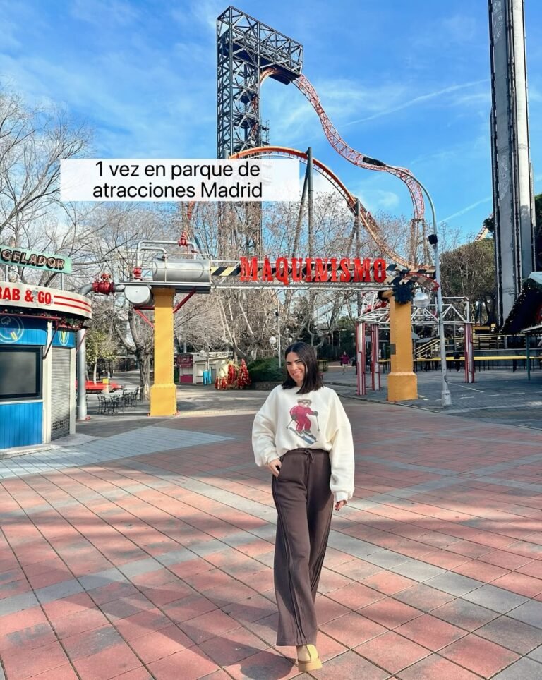 Laura Toledo posando frente a una montaña rusa en un parque de atracciones en Madrid, con un look casual y elegante.