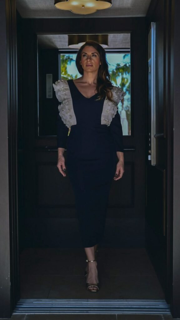 Agencia de marketing digital Brilla Influencers y Comunicación, mujer con vestido elegante y detalles en los hombros, caminando por un pasillo.