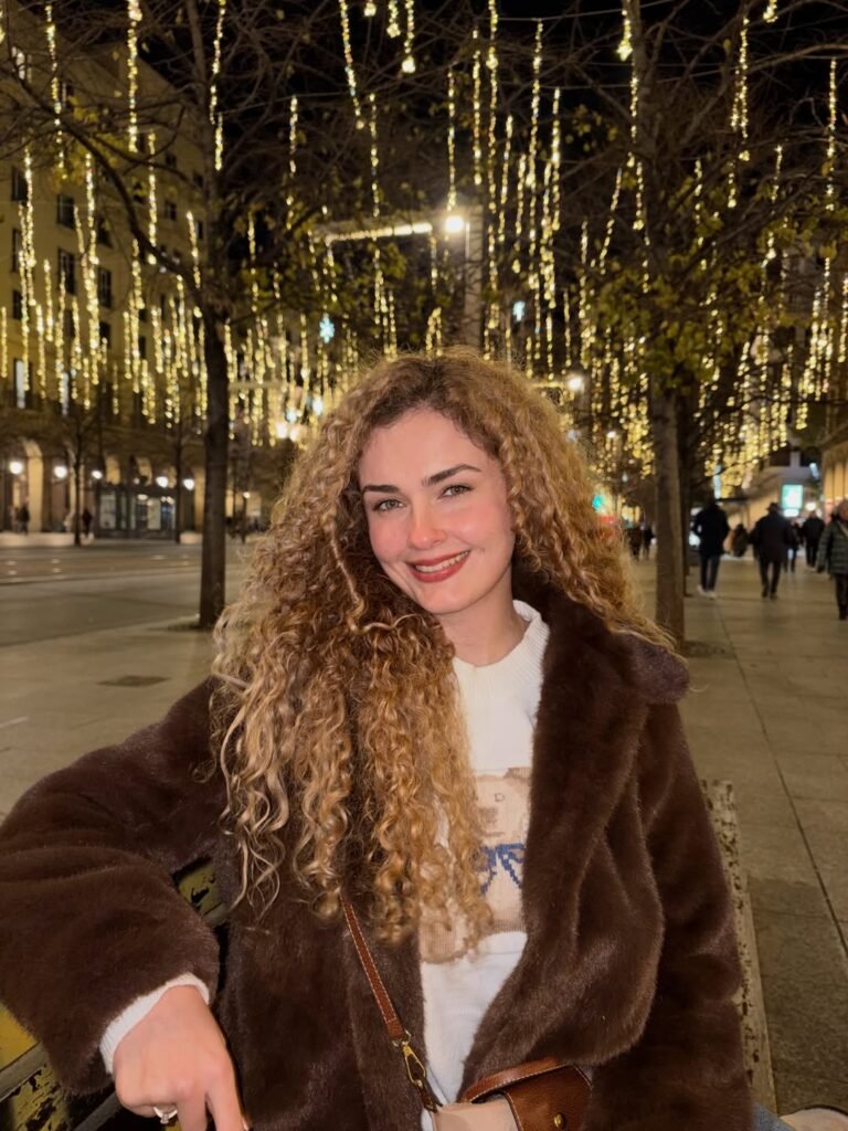 Cristina Ruiz Marin mostrando un producto con un fondo de luces navideñas.