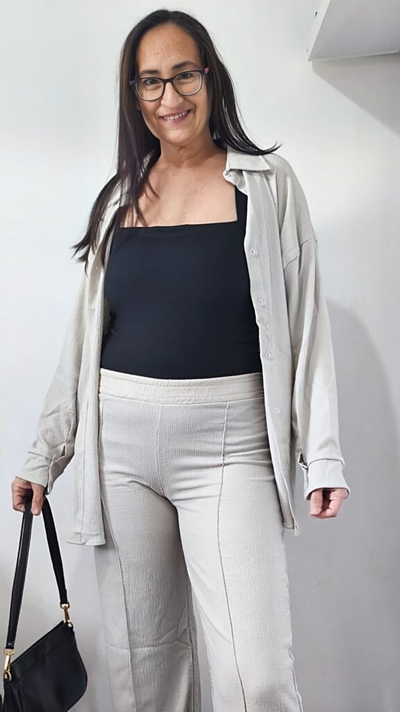 Cristina Asensio Aranda sonriendo y mostrando un look casual con una blusa blanca, pantalones beige y un bolso negro.