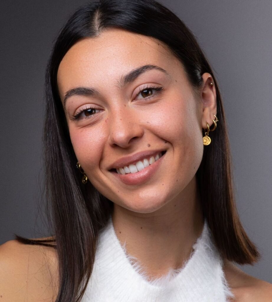 Elia Soler, creadora de contenido UGC, sonriendo con un top blanco y pendientes dorados, mostrando su estilo natural y radiante.