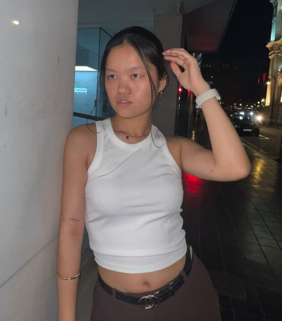 Agencia de marketing digital Brilla Influencers y Comunicación, María Bedins con top blanco y cinturón negro, posando en la calle nocturna.