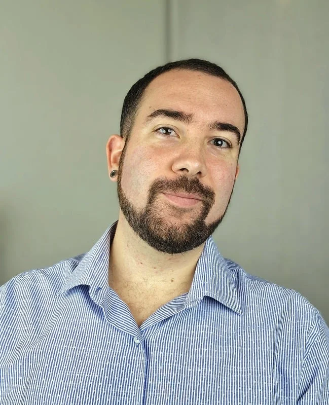 Miguel Tarjuelo posando con una camisa de rayas azul, mirando hacia la cámara con una ligera sonrisa.