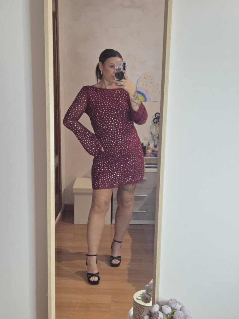 Veronica Villegas con vestido burdeos con detalles brillantes, posando frente al espejo.