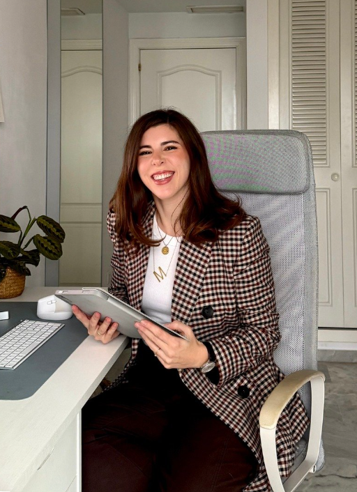 María Anaya, creadora UGC, sonriendo mientras trabaja en su oficina, representando contenido profesional y lifestyle.