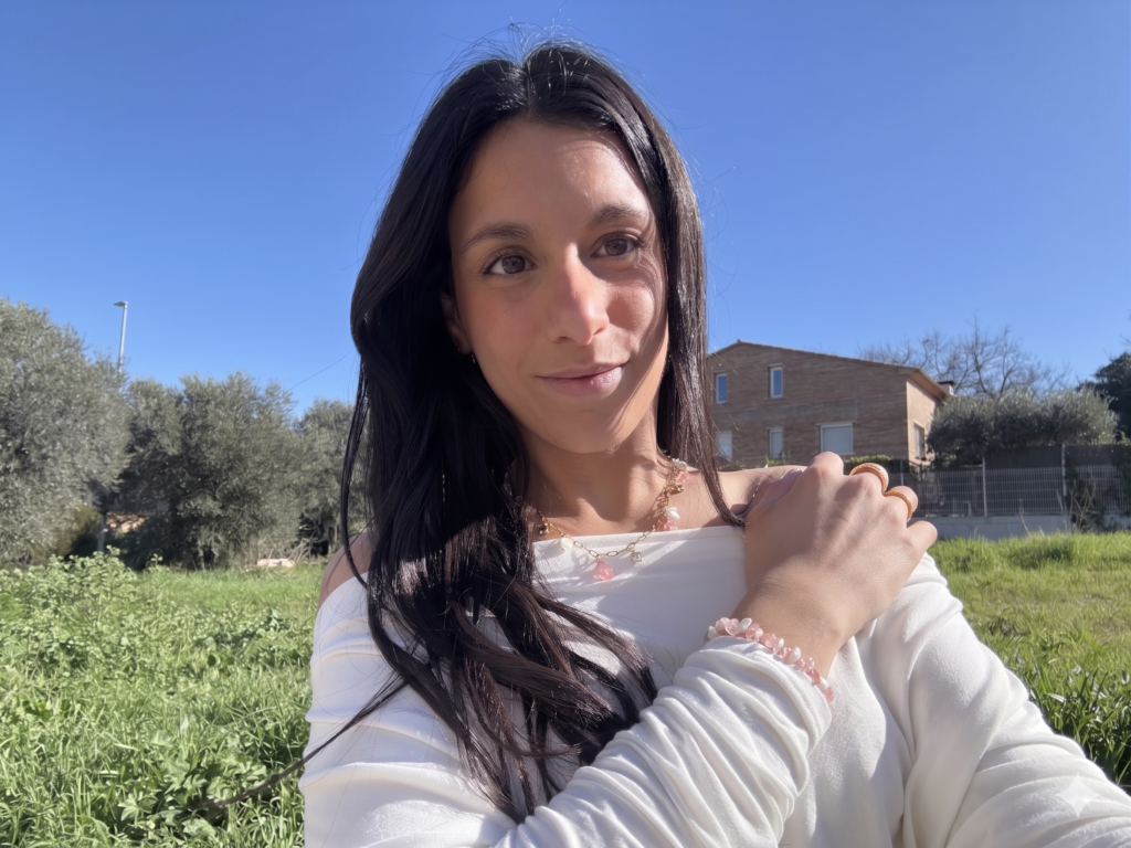 Paula Alsina sonriendo con blusa blanca bajo el sol