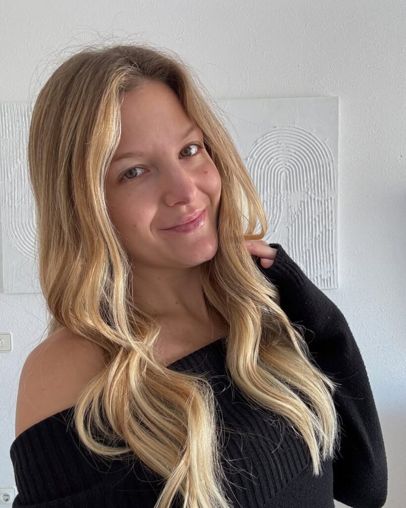 Retrato de mujer rubia con suéter negro sonriendo, estilo natural y elegante
