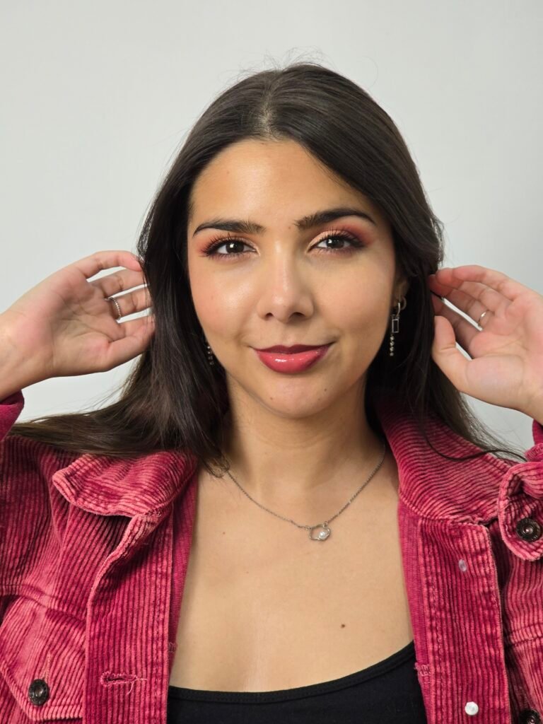 Valeria, mujer joven con cabello oscuro, maquillaje natural y chaqueta burdeos sonriendo a cámara