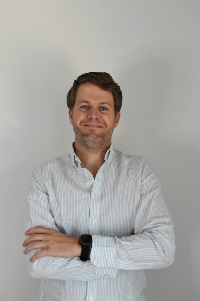 Edu Fairen sonriendo de frente con camisa de rayas.