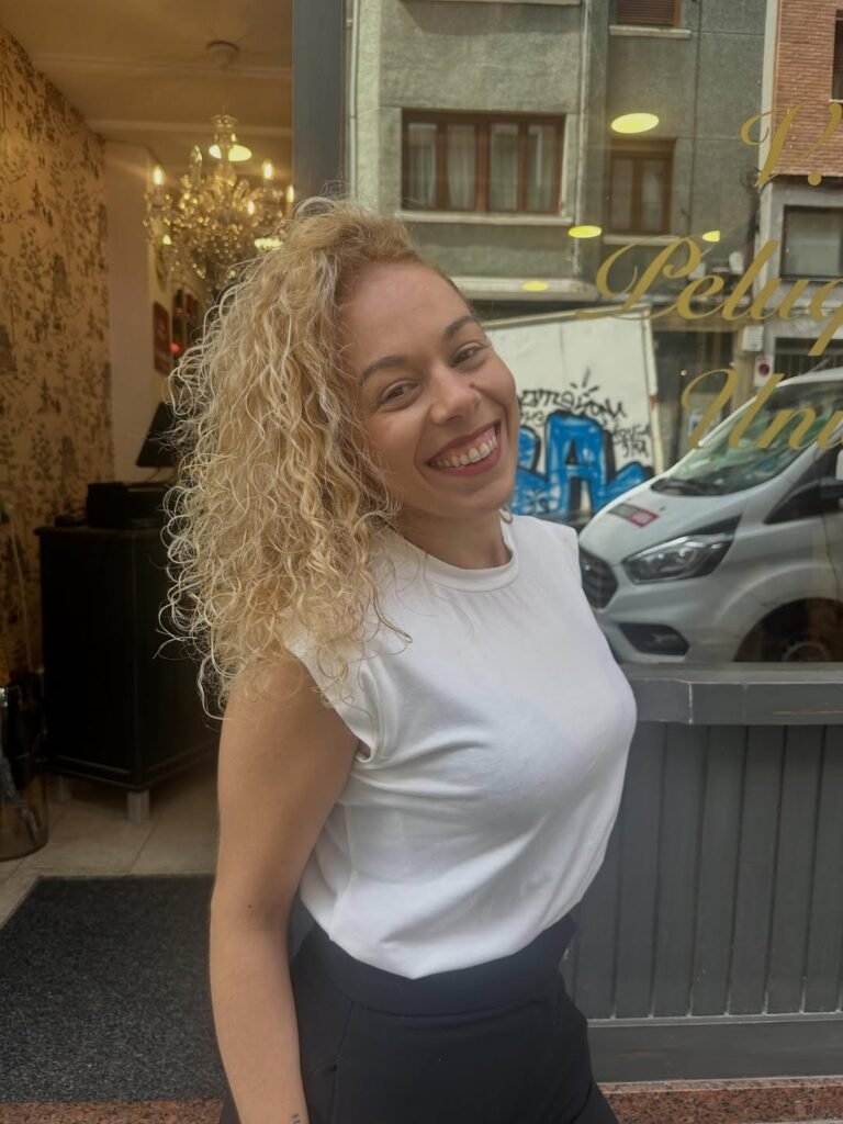 Jessica Circujano Gutiérrez, creadora de contenido UGC especializada en lifestyle, sonriendo frente a un establecimiento urbano con un look casual y elegante.