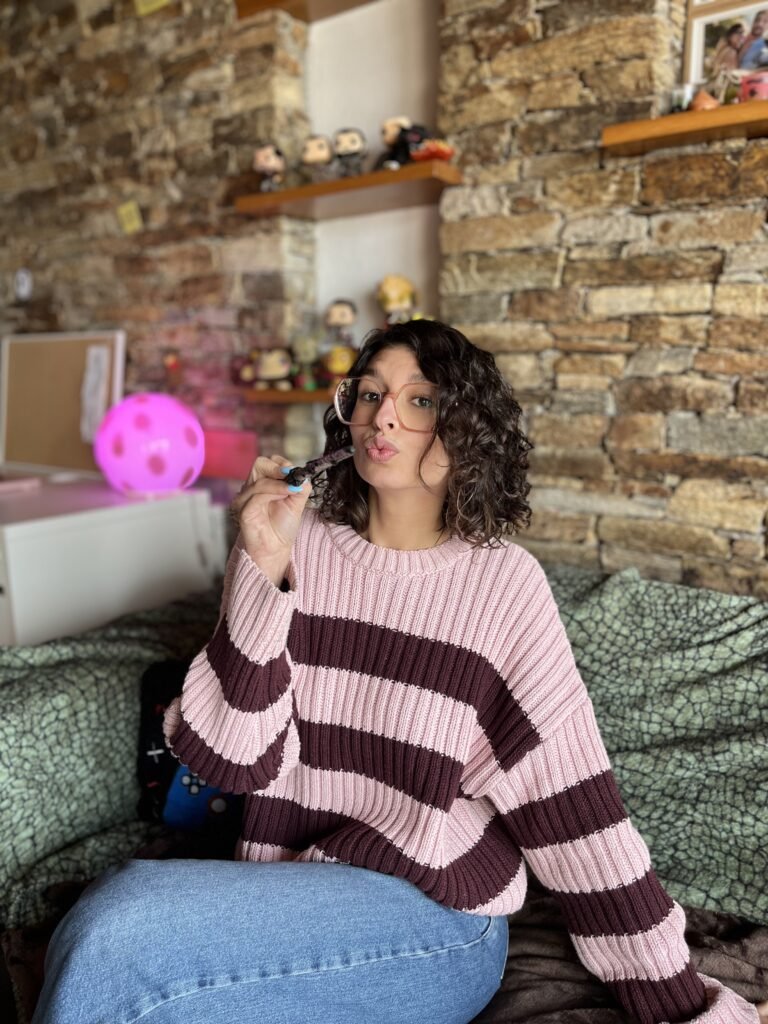 Laura Lomba Taboada posando en un ambiente acogedor con jersey de rayas y gafas, creando contenido UGC lifestyle para marcas de hogar, entretenimiento y estilo de vida.