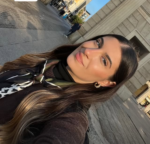 Selfie de una joven mujer posando frente al arco monumental de Porta Garibaldi en Milán, Italia, durante un día soleado.
