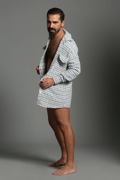 Juan José Marco de pie con chaqueta abierta y fondo gris, mostrando estilo y confianza