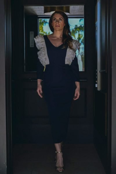 Agencia de marketing digital Brilla Influencers y Comunicación, mujer con vestido elegante y detalles en los hombros, caminando por un pasillo.