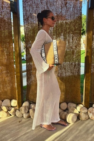 Agencia de marketing digital Brilla Influencers y Comunicación, mujer con top y falda beige frente al mar, con gafas de sol.