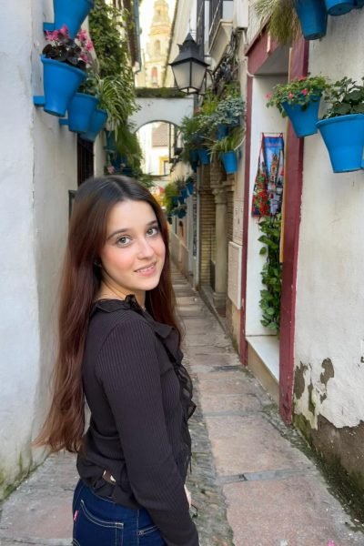 UGC Alba Lucia Navarro caminando por calle típica con flores y arquitectura andaluza. Imagen de la Agencia de marketing digital Brilla influencers y Comunicación.