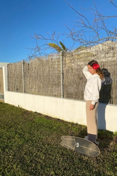 Alicia García con flor roja en su cabello, junto a una tabla de skate en un jardín.