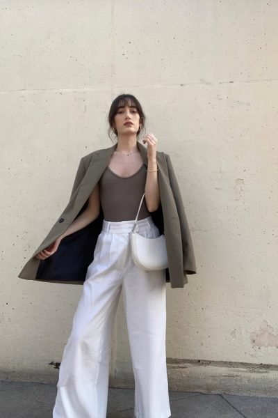 Ana Flores Campos con blazer oversize verde oliva, pantalón blanco y bolso blanco en una sesión de moda urbana de estilo minimalista.