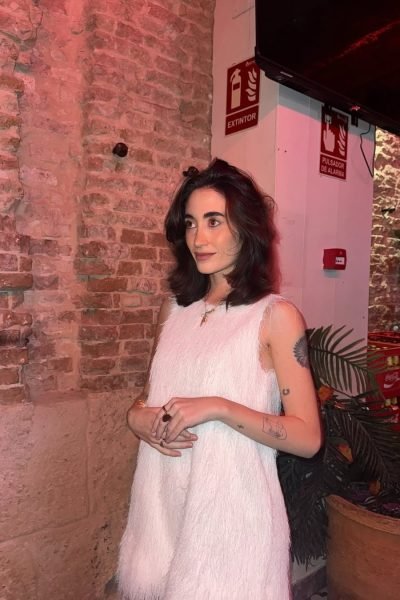 Ana Flores Campos con vestido blanco de textura suave en un entorno interior de estilo industrial y elegante.