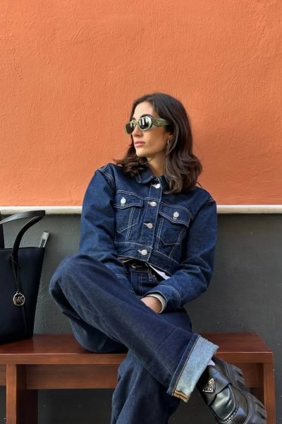 Ana Flores Campos luciendo un conjunto denim total look con gafas de sol y accesorios negros en una sesión de moda urbana.