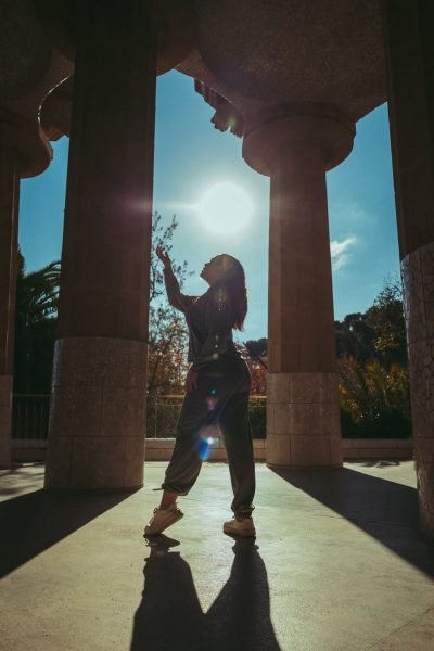 Arantxa Styles posando al sol con un look deportivo, bajo columnas arquitectónicas.
