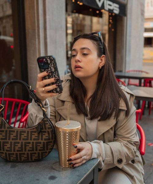 Arantxa Styles, influencer y creadora de contenido UGC, disfrutando de un café mientras revisa su teléfono móvil.