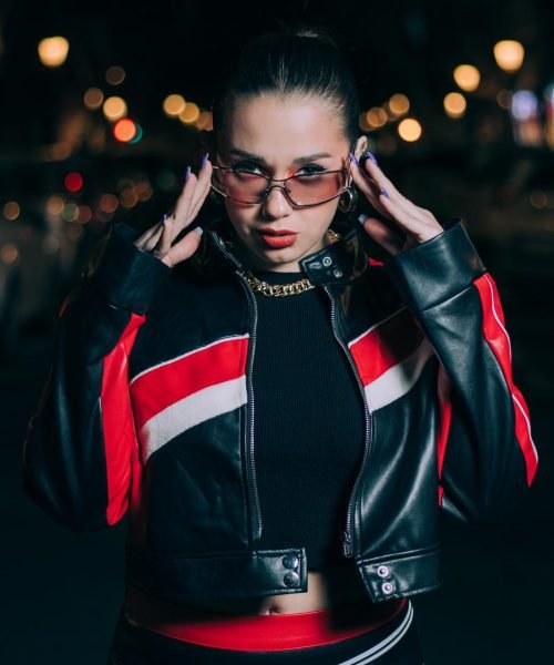 Bárbara Elena posando en la calle con chaqueta de cuero roja y pantalón corto, con gafas de sol.
