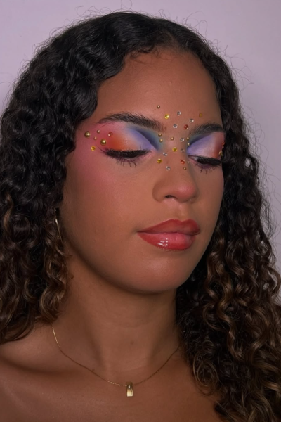 Meritxell Pérez, creadora UGC beauty, con maquillaje artístico en tonos rosa, naranja y violeta decorado con pedrería | Agencia Brilla Influencers