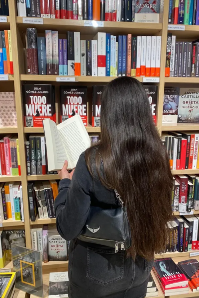María del Valle del Moral Cobija leyendo un libro frente a una estantería de librería | Agencia Brilla Influencers
