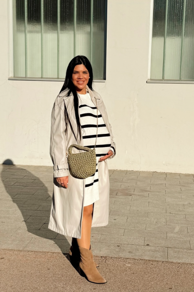 Laia Barruelo Blasco mostrando un look premamá con vestido de rayas, gabardina y botines | Agencia Brilla Influencers.