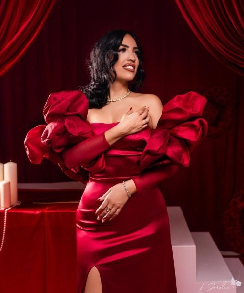 Carolina Vera posando con vestido rojo elegante con detalles voluminosos en los hombros. UGC sofisticado y de alta costura.