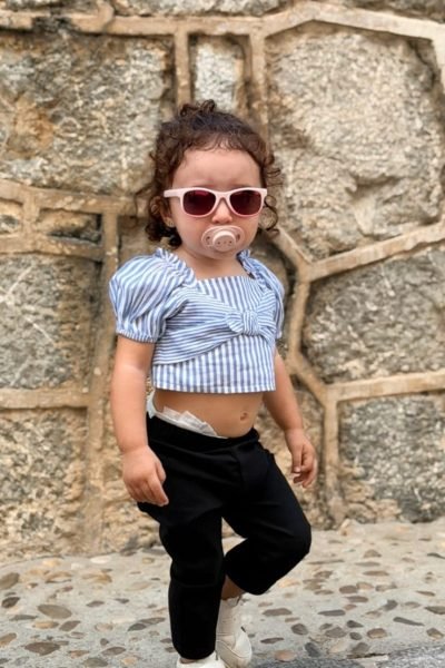 Cinzia Ledonne con un conjunto deportivo y gafas de sol, posando en una pared de fondo.