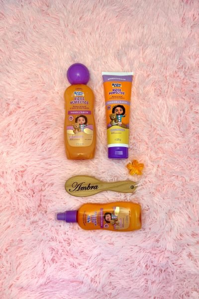 Producto para cabello rizos perfectos de la marca Ambra con frasco y cepillo en fondo suave.