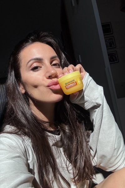 Cinzia Ledonne mostrando la crema Garnier Vitamin C, con luz natural en su rostro.