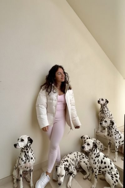 Cinzia Ledonne con un conjunto deportivo rosa rodeada de sus perros dálmatas.