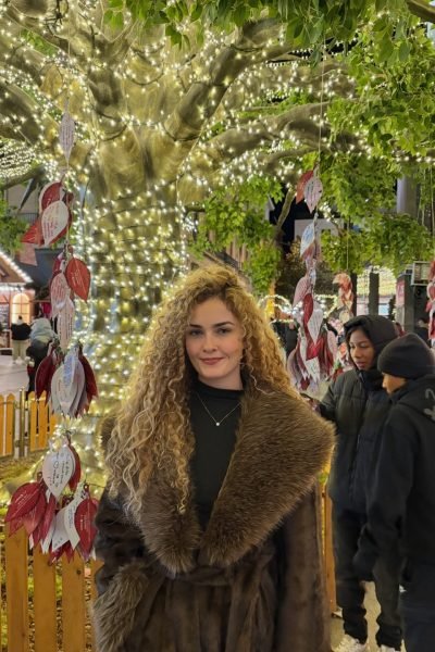 Cristina Ruiz Marin en un ambiente navideño con luces de fondo, mostrando su outfit de invierno.