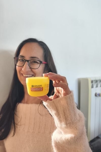 Cristina Asensio Aranda mostrando la crema Garnier Vitamina C mientras sonríe.