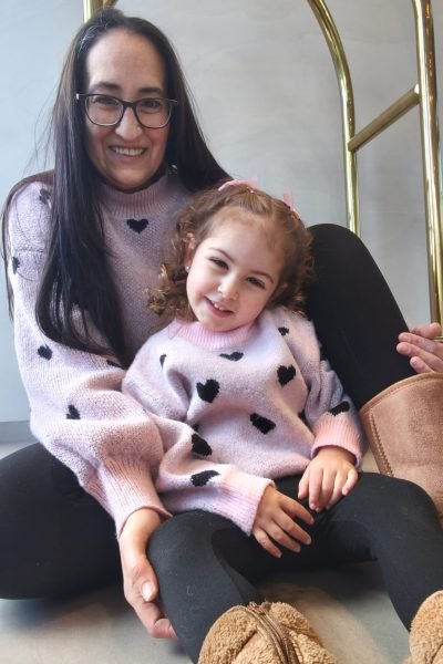 Cristina Asensio Aranda con su hija pequeña, ambas sonriendo y luciendo suéteres a juego.