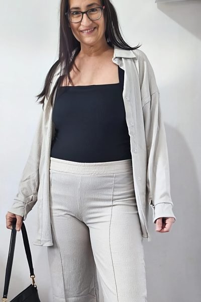 Cristina Asensio Aranda sonriendo y mostrando un look casual con una blusa blanca, pantalones beige y un bolso negro.