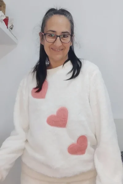 Cristina Asensio Aranda con suéter blanco con corazones rosados, sonriendo a la cámara.
