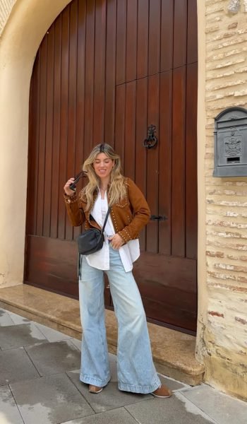 Dessire Verdu Zarco posando frente a una puerta con una chaqueta marrón, pantalones anchos y gafas de sol, creando contenido de moda para Agencia de marketing digital Brilla Influencers y Comunicación