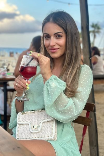 Elisabet Aguilar Águila en la playa disfrutando de una bebida y posando frente a la cámara.