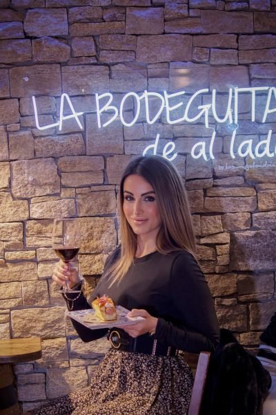 Elisabet Aguilar disfrutando de comida y vino en La Bodeguita de al Lado, mostrando su estilo lifestyle y foodie.