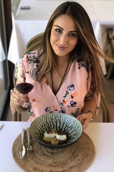 Elisabet Aguilar disfrutando de un menú degustación en Es Portal Hotel, con un plato gourmet frente a ella y copa de vino en mano.