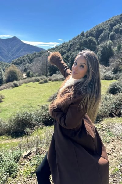 Elisabet Aguilar Águila señalando un paisaje natural con fondo de montaña y vegetación.
