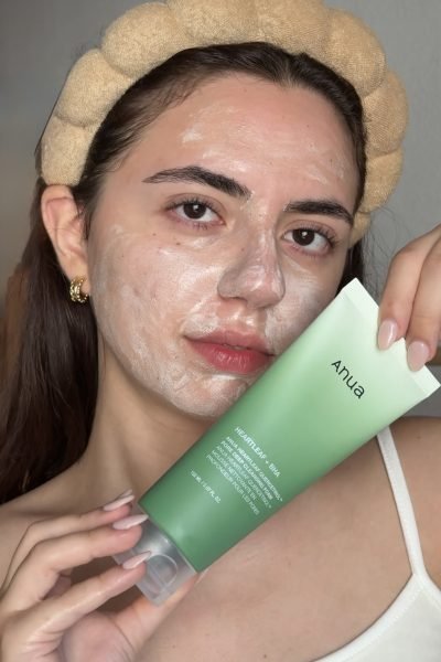Esther Zecchin aplicando una mascarilla limpiadora facial mientras muestra un producto de skincare coreano para el cuidado de la piel.