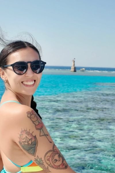 Fátima del Pilar sonriendo frente al mar, con gafas de sol y un look veraniego, disfrutando de un día de sol.