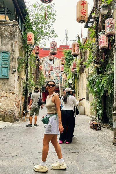 Fátima del Pilar caminando por las pintorescas calles de Malasia, rodeada de faroles tradicionales.